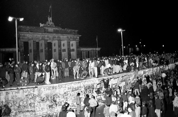 EAST AND WEST GERMANS CLIMB THE BERLIN WALL FILE PHOTO.